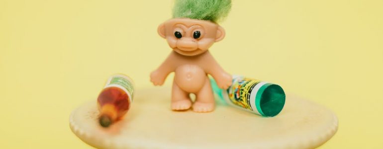 mini troll toy on table with bottles