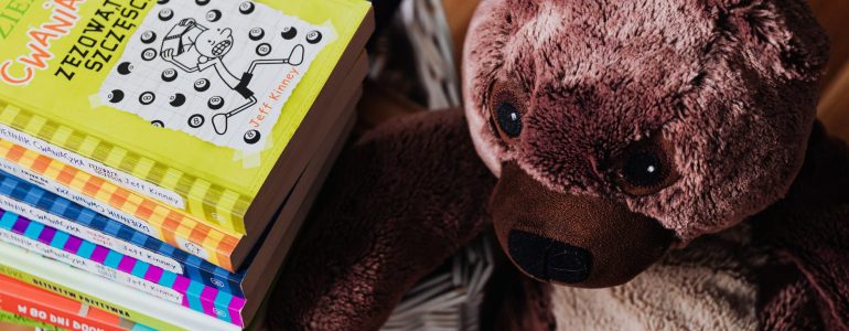 brown bear plush toy and stack of books