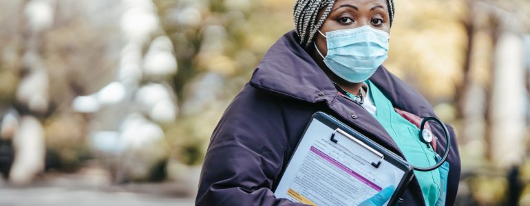 black female doctor in street with documents in epidemic